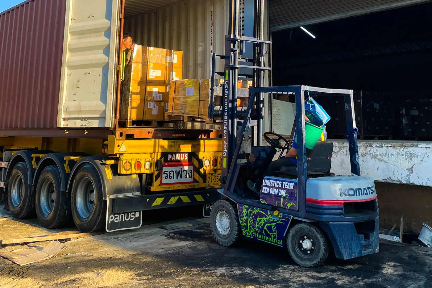 Forklift loading palletized goods into a shipping container at a warehouse